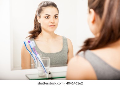 Portrait of a pretty young woman standing in front of a bathroom mirror and looking at herself
