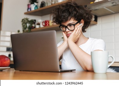 Porträt einer hübschen jungen Frau mit Brille, die morgens am Laptop arbeitet