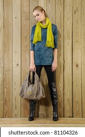 Portrait of pretty young Woman Wearing scarf holding handbag at wooden background