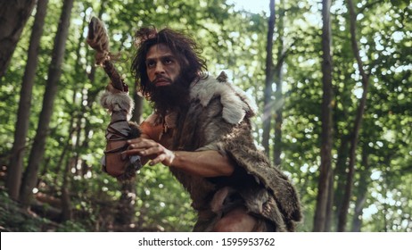 Portrait of Primeval Caveman Wearing Animal Skin and Fur Hunting with a Stone Tipped Spear in the Prehistoric Forest. Prehistoric Neanderthal Hunter Ready to Throw Spear in the Jungle