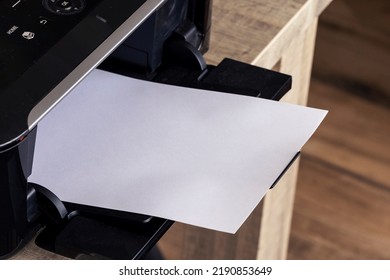 A portrait of a printer with an white empty piece of paper in its printed output tray. The blank page can be used to display some print out.