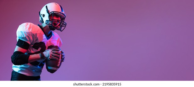 Portrait Of Professional American Football Player Shouting Before Game To Rise Team Spirit Isolated Over Purple Background Neon Light. Concept Of Active Life, Team Game, Energy, Sport, Competition.