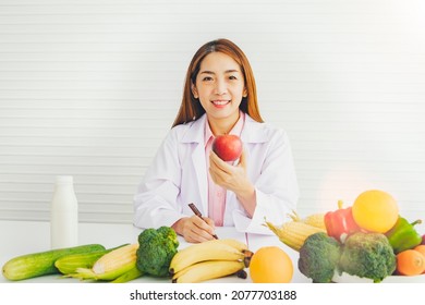 Portrait Professional Asian Female Nutritionist Holds An Apple Rich In Vitamin C And Healthy Fiber While Working On A Diet Plan. Losing Weight And Eating A Proper Diet For Everyday Life.