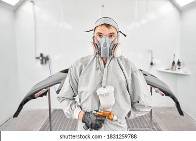 Portrait of professional auto painter. Worker painting parts of the car in special painting chamber, wearing costume and protective gear. Car service station. - Powered by Shutterstock