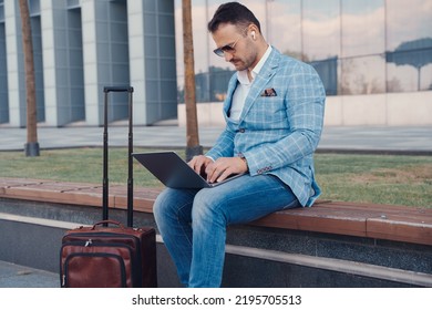 Portrait Of Professional Businessperson Typing On Laptop Sitting On Bench In City.