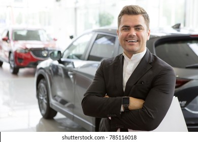 Portrait of a professional car salesman posing confidently at the dealership salon new cars on the background copyspace positivity friendly assistant worker manager retailer seller sales occupation.