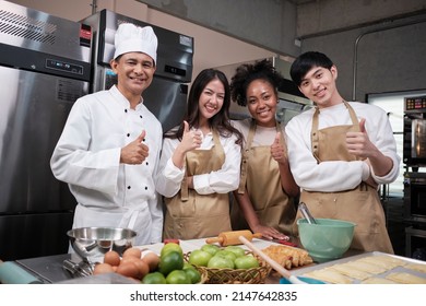 Portrait of professional cooking class people, senior male chef, and young students team looking at camera, cheerful smile and thumb up in kitchen, pastry foods and bakery course for small business. - Powered by Shutterstock