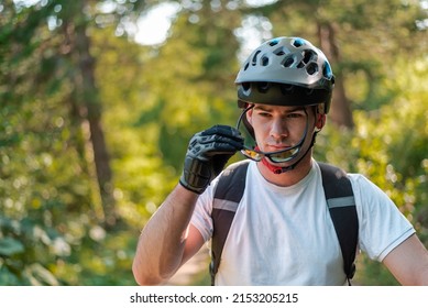 Portrait Of A Professional Cyclist In A Helmet Putting His Glasses With A Serious Face In The Mountain Forest.