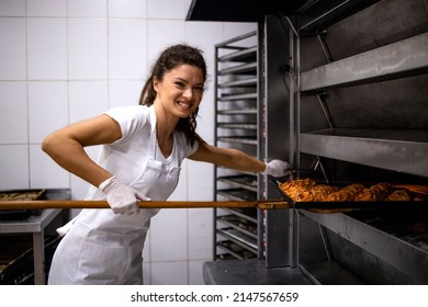 Portrait Of Professional Female Baker Holding Wooden Tray And Putting Bread In The Oven.