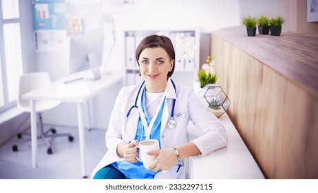 Portrait of professional female doctor holding cup of coffee - Powered by Shutterstock