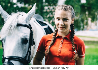 Portrait of professional female jockey standing near horse preparing to equitation and looking at camera during free time in country club, concept of equestrian sport and friendship with animal - Powered by Shutterstock