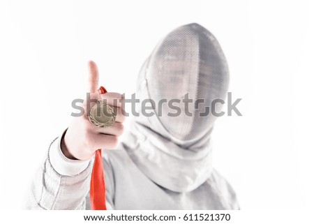 Portrait of professional fencer in fencing mask holding medal with thumb up  isolated on white 