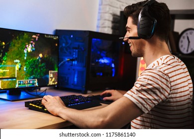 Portrait Of Professional Gamer Guy Playing Video Games On Computer Wearing Headphones And Using Backlit Colorful Keyboard