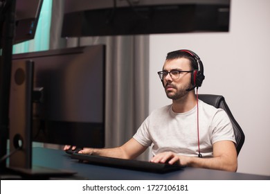 Portrait Of Professional Gamer Playing Shooter Games On Powerful Computer With Multiple Monitors.