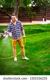 Portrait Of Professional Gardener Watering Lawn Using Hose