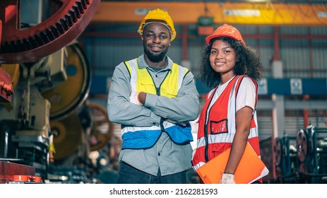 Portrait of professional happy smiling Black African American engineers, workers, technician man and woman wear hard hat, use clipboard discuss work in steel metal plant manufacturing factory industry - Powered by Shutterstock