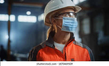 Portrait Of A Professional Heavy Industry Engineer Worker Wearing On Safety Face Mask In A Steel Factory. Beautiful Female Industrial Specialist In Hard Hat Standing In Metal Construction Facility.