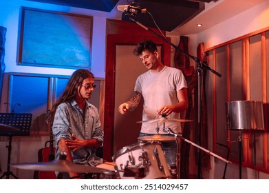 Portrait of professional hippie drummer sitting by drums and discussing with sound engineer at music recording studio. Musicians at studio talking and consulting about recording music at studio. - Powered by Shutterstock