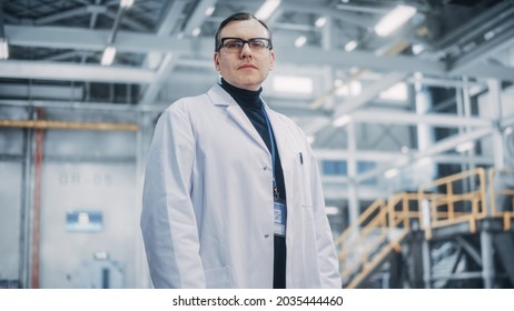 Portrait Of A Professional Male Heavy Industry EngineerWorker Wearing White Laboratory Coat And Safety Glasses. Confident Caucasian Industrial Specialist Standing In A Factory Facility.