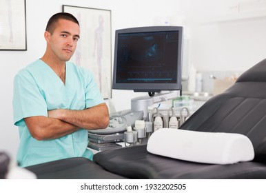 Portrait Of Professional Male Sonographer Sitting With Arms Crossed In Medical Diagnostics Office