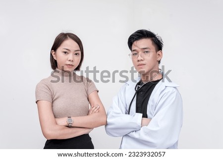 Portrait of professional man, doctor, physician, and woman posing side by side looking fierce and serious. Isolated on a red background.