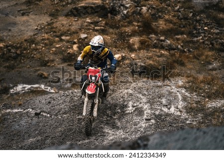 Portrait of professional motorcyclist in full moto equipment riding crops enduro bike in mountains,  driver rides and dirt and stones fly off the wheel, motorcycle race, concept of motosport Stock photo © 
