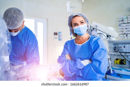 Portrait Of The Professional Nurse Medical Assistant In Surgical Mask During Operation. Modern Hospital Operating Room.