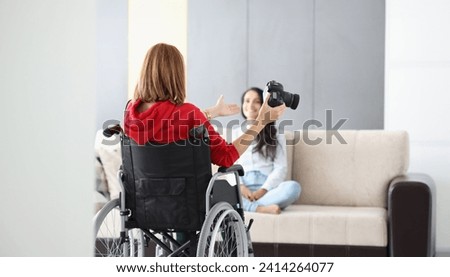 Portrait of professional photographer in wheelchair give advice on posing to model on sofa. Creative artist with photocamera. Disabled people, art concept