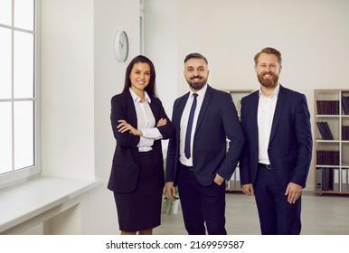 Portrait of professional and successful team of business or lawyers posing together in modern office. Two men and one woman dressed in stylish business attire are smiling while looking at camera. - Shutterstock ID 2169959587