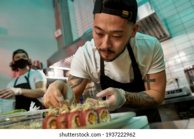 Portrait of professional sushi chef carefully adding final touch with dedication to his perfect set of sushi. Japanese cuisine, restaurant service, business concept - Powered by Shutterstock