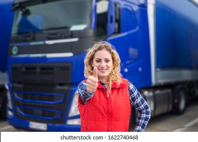 Portrait Of Professional Truck Driver Showing Thumbs Up And Smiling. Truck Vehicle In Background. Transportation Services. Trucker Occupation.