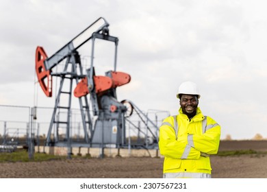 Portrait of professional worker in protective work wear standing in oil field.