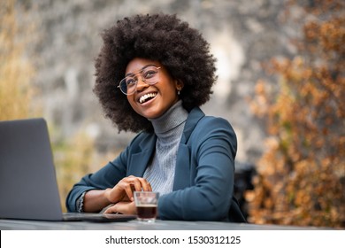 Portrait of professional young black business woman sitting outside with laptop and smiling