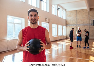 Portrait of a proud basketball player holding a ball on the basketball court. - Powered by Shutterstock