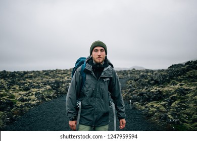 Portrait of proud and brave young adventurer hiker, explorer handsome man with trekking backpack stand on rocky hiking trail or path, look into camera. Outdoor vibes and adventures wanderlust - Powered by Shutterstock