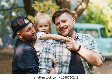 Portrait of proud gay parents and their child in the backyard. LGBT, gay family concept.