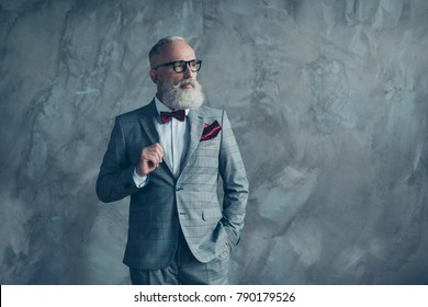 Portrait of proud respected confident handsome masculine virile vintage grey-haired sharp dressed in bespoke checkered grey suit with vinous handkerchief brutal macho isolated on concrete background