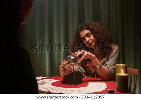 Portrait of psychic talking to client touching crystal ball and talking to client