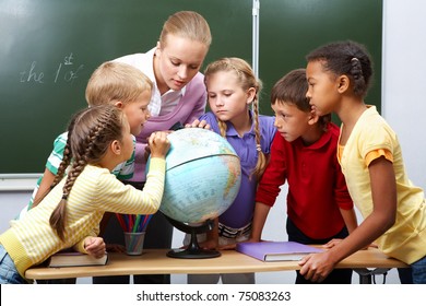 Portrait of pupils looking at globe while listening to teacher during geography lesson - Powered by Shutterstock