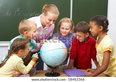 Portrait of pupils looking at globe while listening to teacher during geography lesson