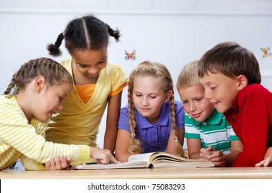 Portrait of pupils looking at page of encyclopaedia at reading lesson