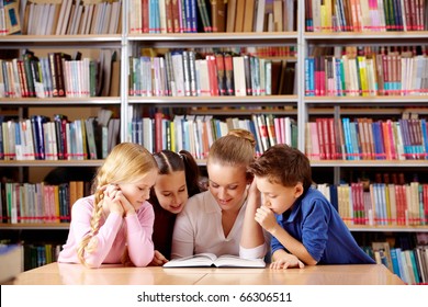 Portrait of pupils and teacher looking at page of interesting book in library - Powered by Shutterstock