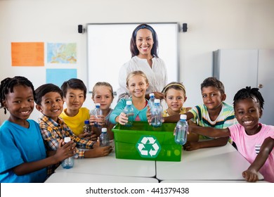 Portrait of pupils and teacher recycling in classroom