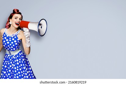 Portrait Of Purple Haired Woman Holding Mega Phone, Shout Advertising Something. Girl In Blue Pin Up Style Dress With Mega Phone Loudspeaker. Isolated On Grey Background. Beauty Model In Retro Concept