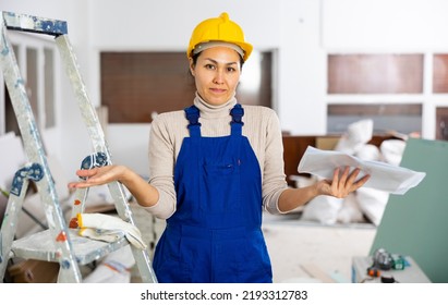 Portrait Of Questionable Asian Woman Builder Holding Documents Indoors.