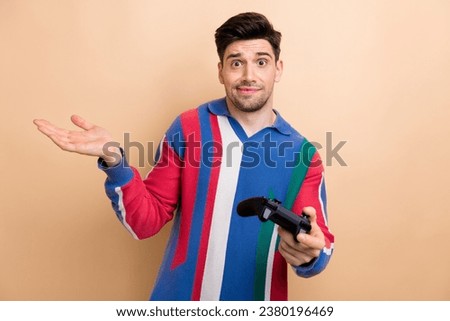 Portrait of questioned clueless person hold controller shrug shoulder not know isolated on beige color background