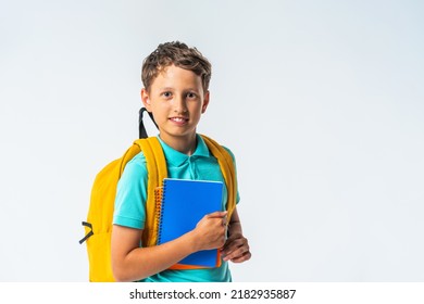 portrait of a quirky smiling schoolboy with a backpack, headphones and notebooks in his hands, posing on a white background. Back to school. the positive boy is happy to start classes. Advertising