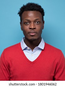 Portrait of real black african man with no expression for ID or passport photo. Studio shot on blue wall.