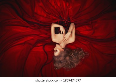 Portrait Of A Reclining Beautiful Blonde Girl In A Dark Red Ball Gown