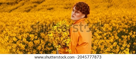 Portrait of red haired women dressed in trendy fall orange trench coat in colourful orange field. Fashion clothes autumn look